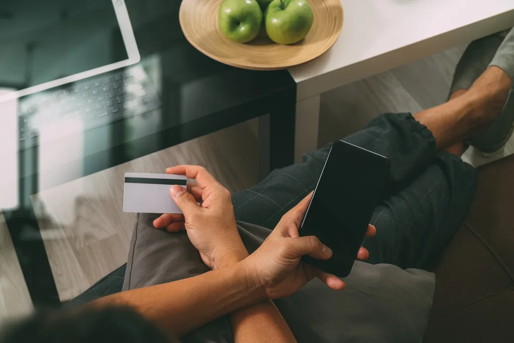 pessoa com celular e cartão de crédito nas mãos